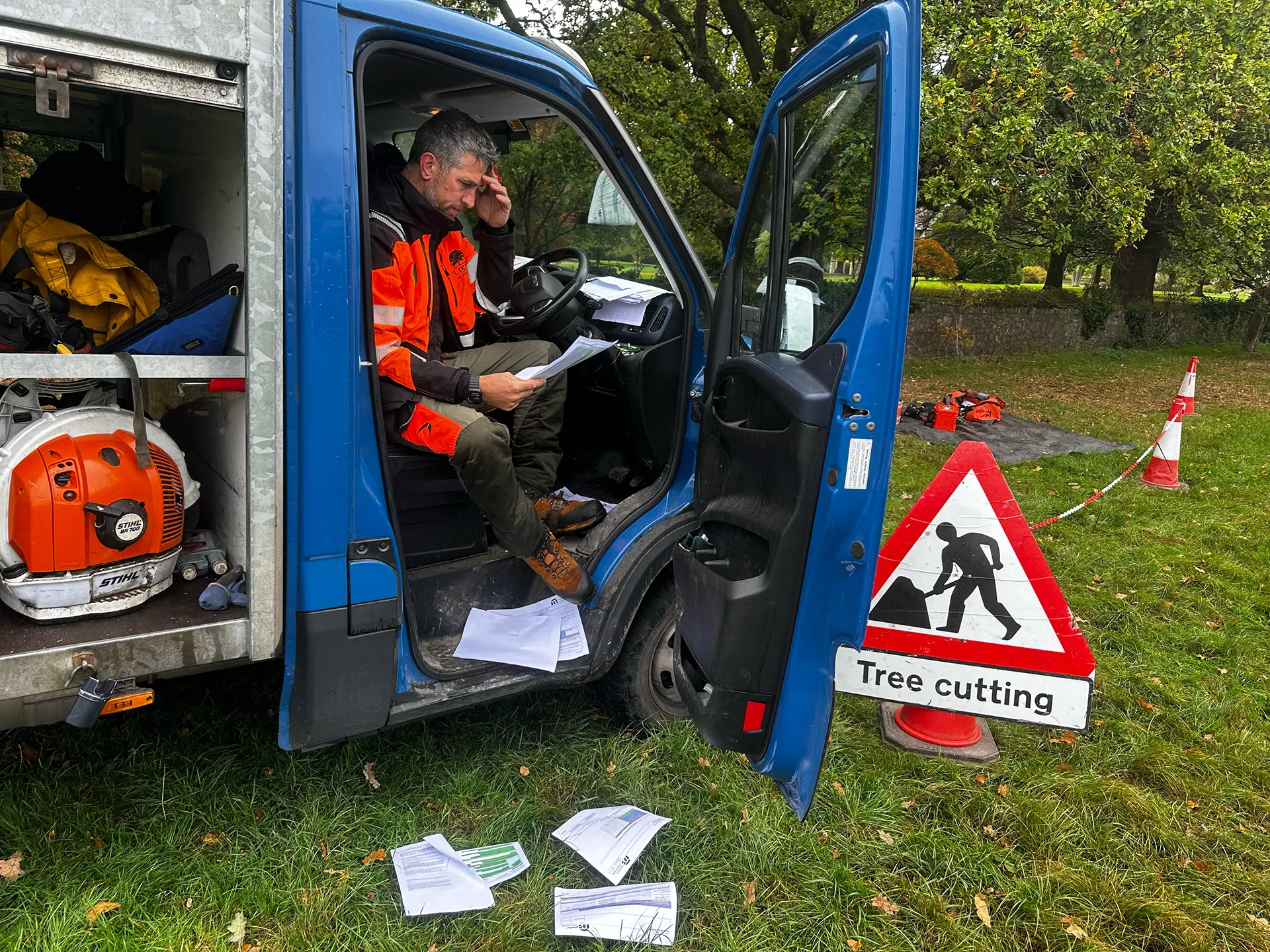 Tree surgeon reviewing paper risk assessment forms in a work van
